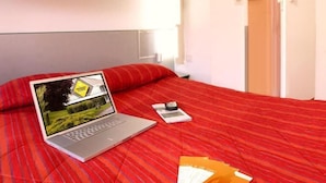 Ein Hotelzimmer mit einem Bett, einem Laptop, einem Mobiltelefon und einigen Broschüren.