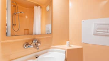 Un bagno con una vasca da bagno bianca, uno specchio, un soffione della doccia e un portasciugamani.