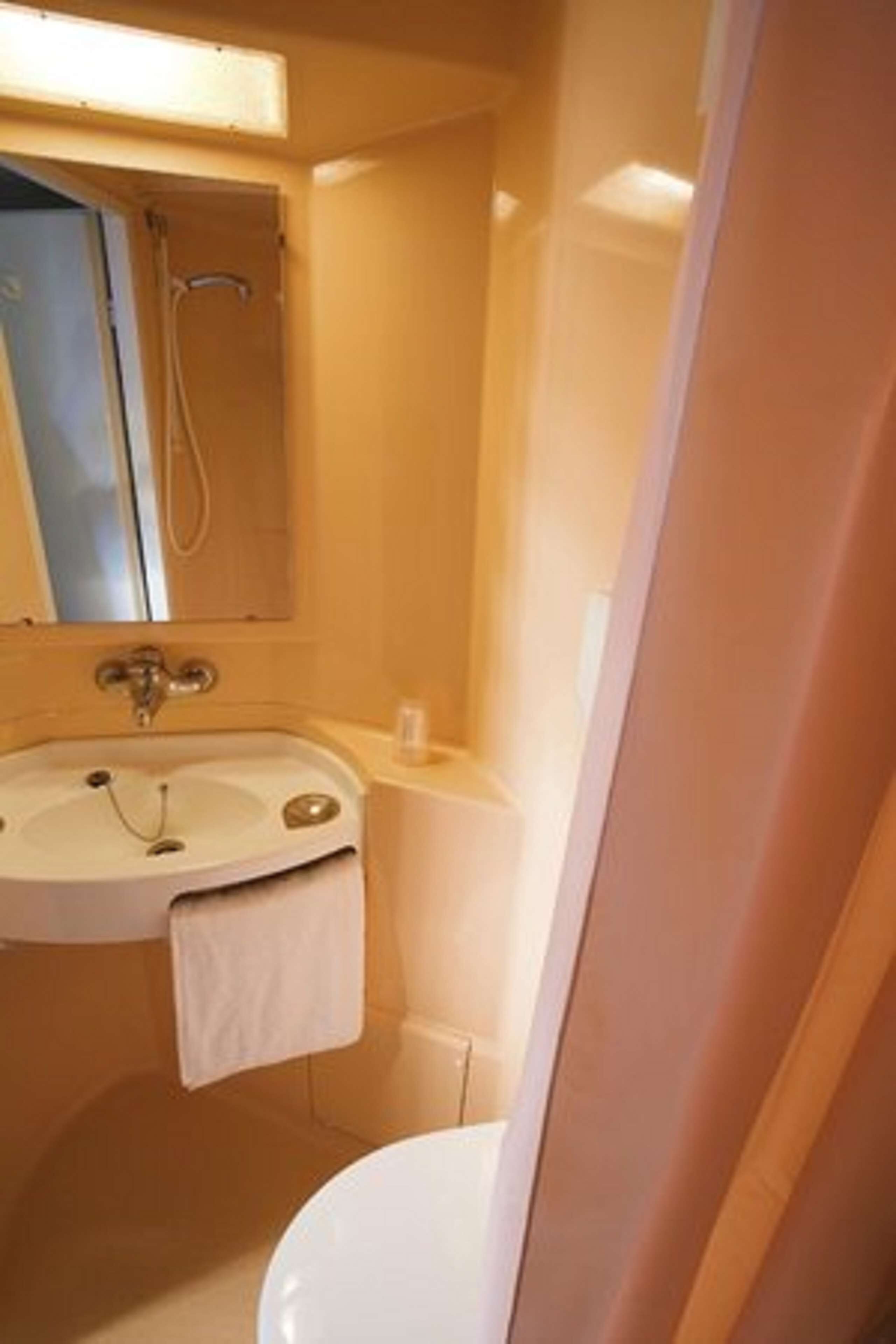 Un baño con lavamanos, espejo e inodoro.