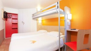 A hotel room with a bunk bed, a desk with a chair, a red wardrobe, and a wall-mounted TV. - Unisotel Tours Nord (Parcay-Meslay)