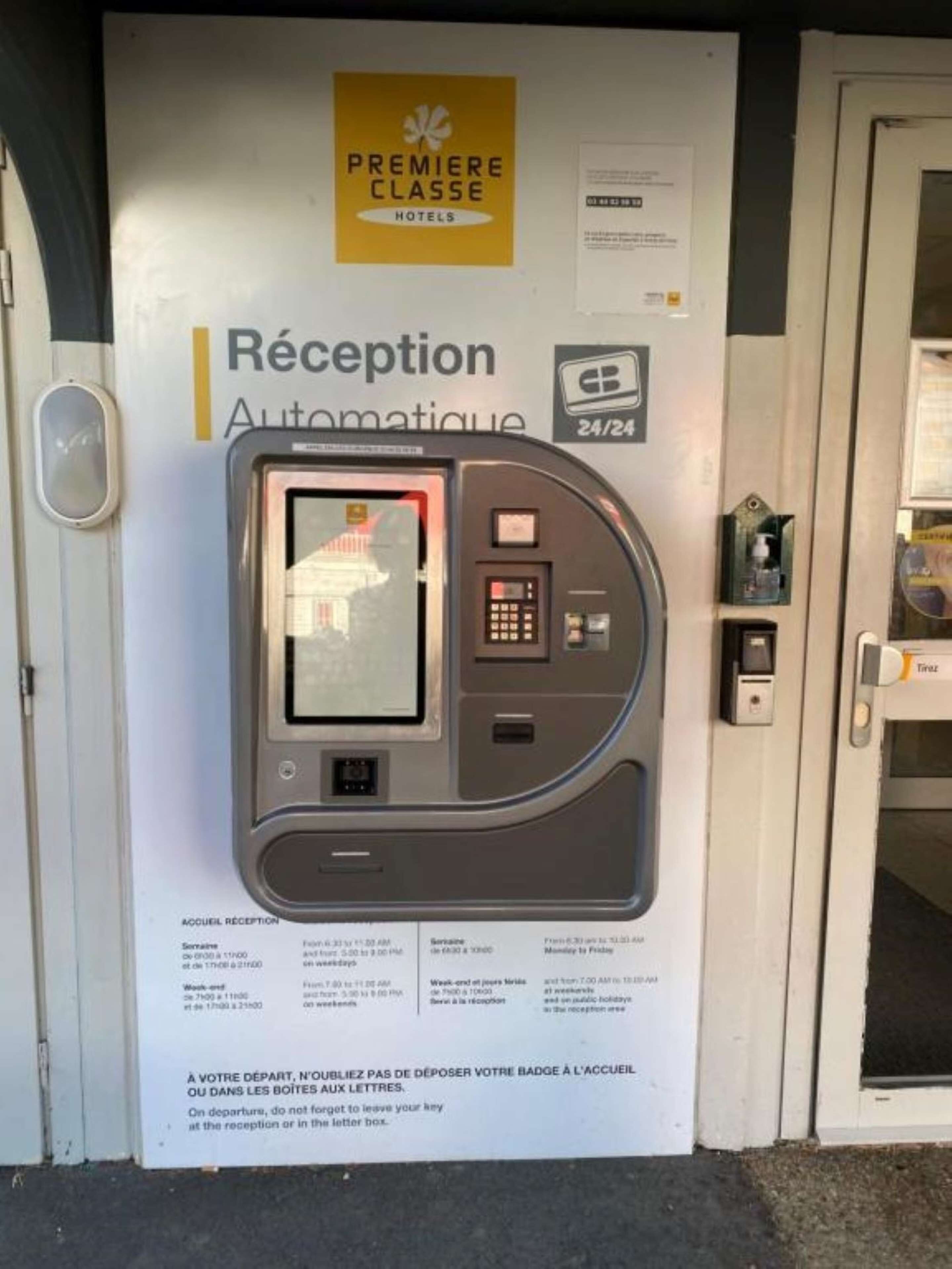 An automated reception kiosk with a digital screen and keypad, located at the entrance of a hotel.