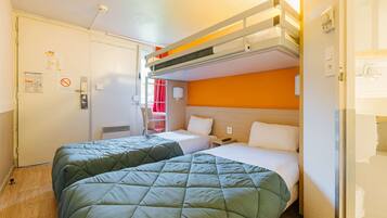 A hotel room with bunk beds, a desk, and a chair.