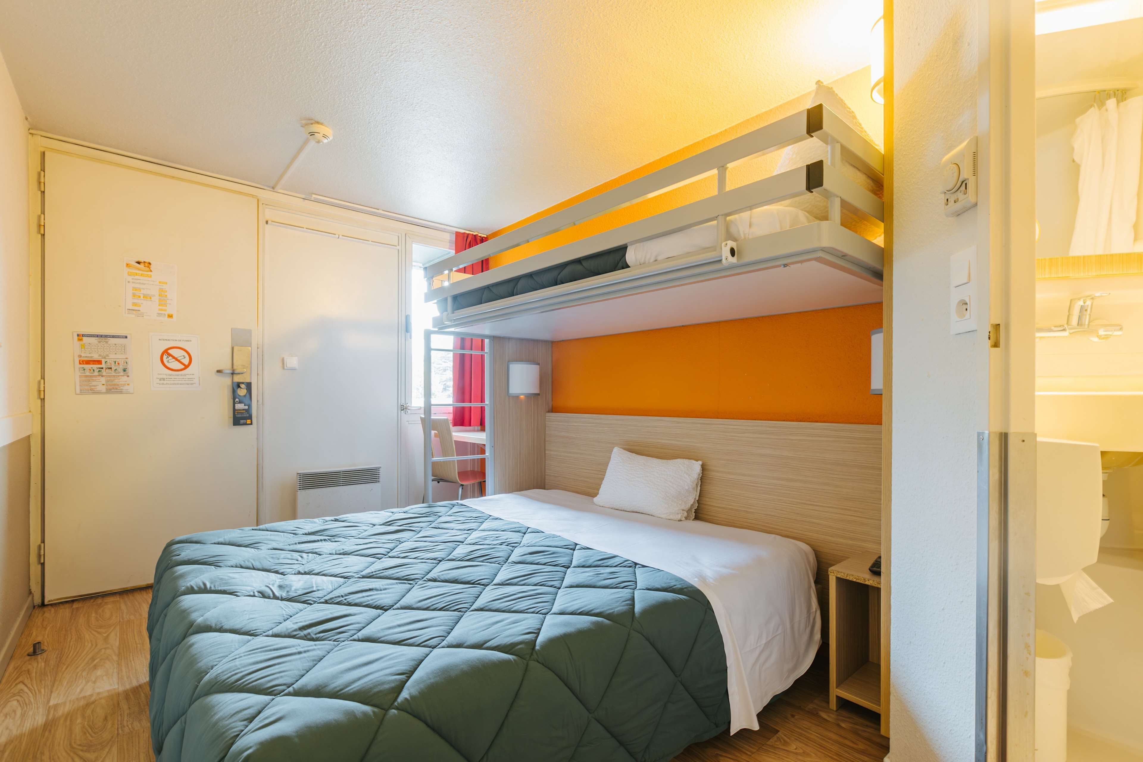 Una habitación de hotel con literas, una cama individual, un escritorio y una silla.