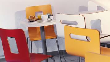 A dining area with a white table and chairs, one of which is red.