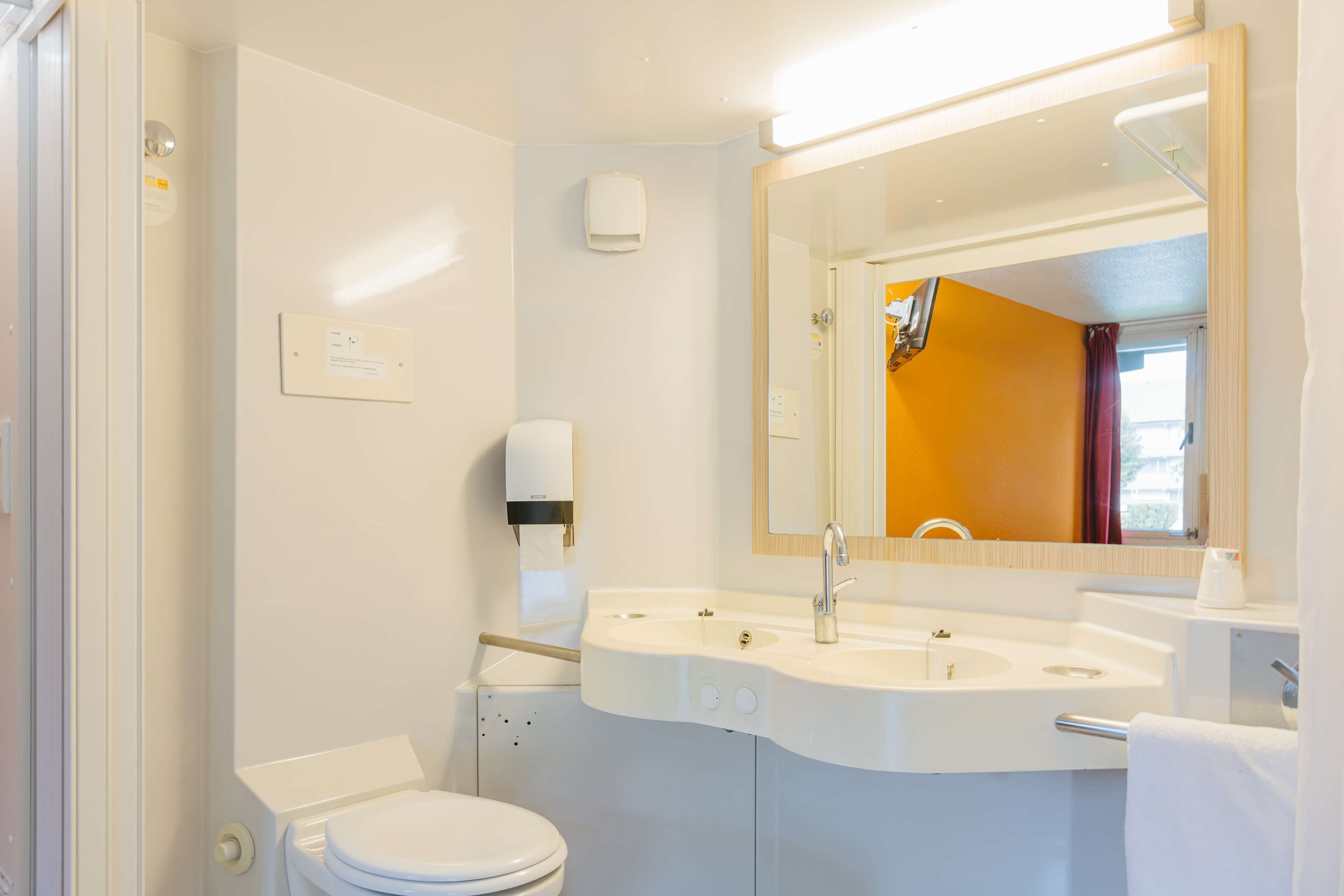 A modern bathroom with a white sink, a mirror, and a toilet.