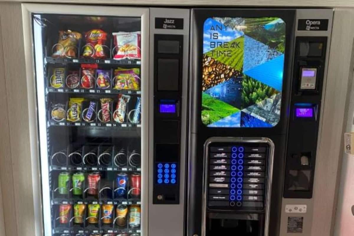 Ein Getränkeautomat mit Snacks und Getränken, einem digitalen Display und einer Zahlungsabwicklung.