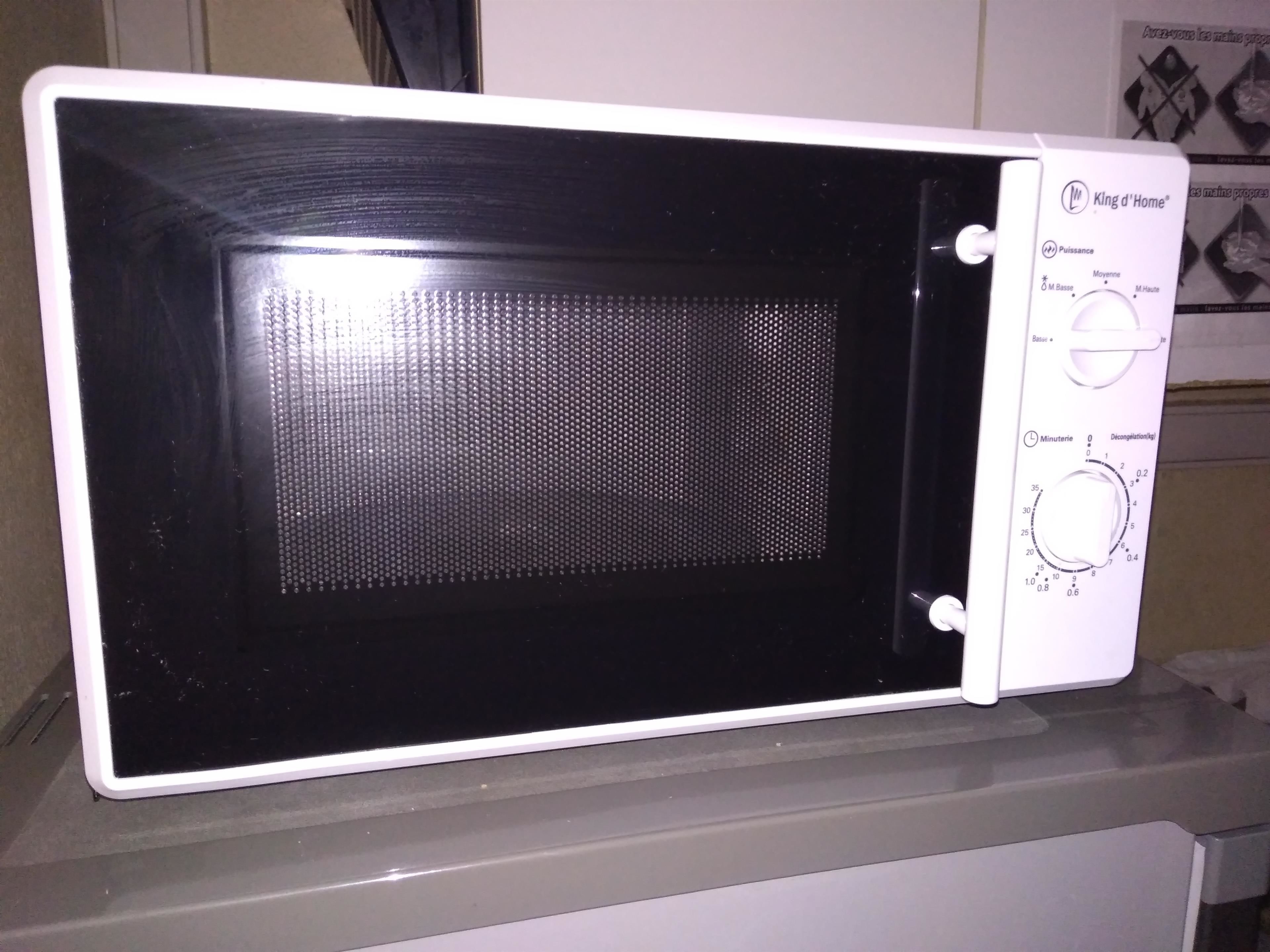Un microondas blanco con pantalla digital y panel de control, sobre una encimera de cocina.