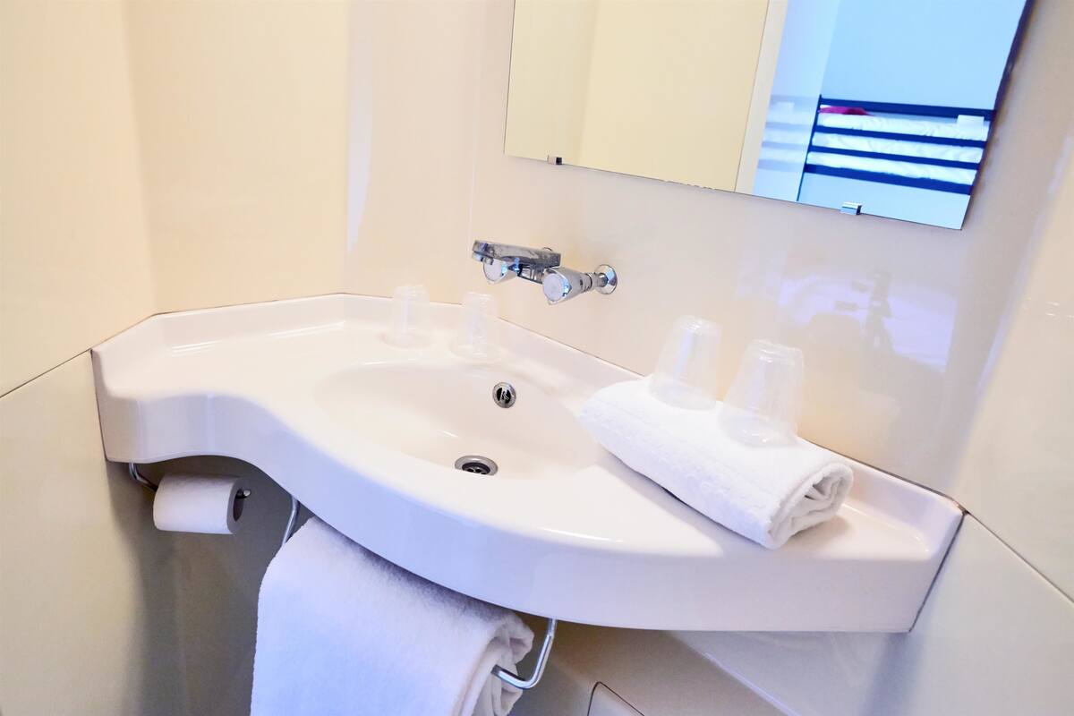 A bathroom with a white sink, a towel rack, and a toilet paper holder.