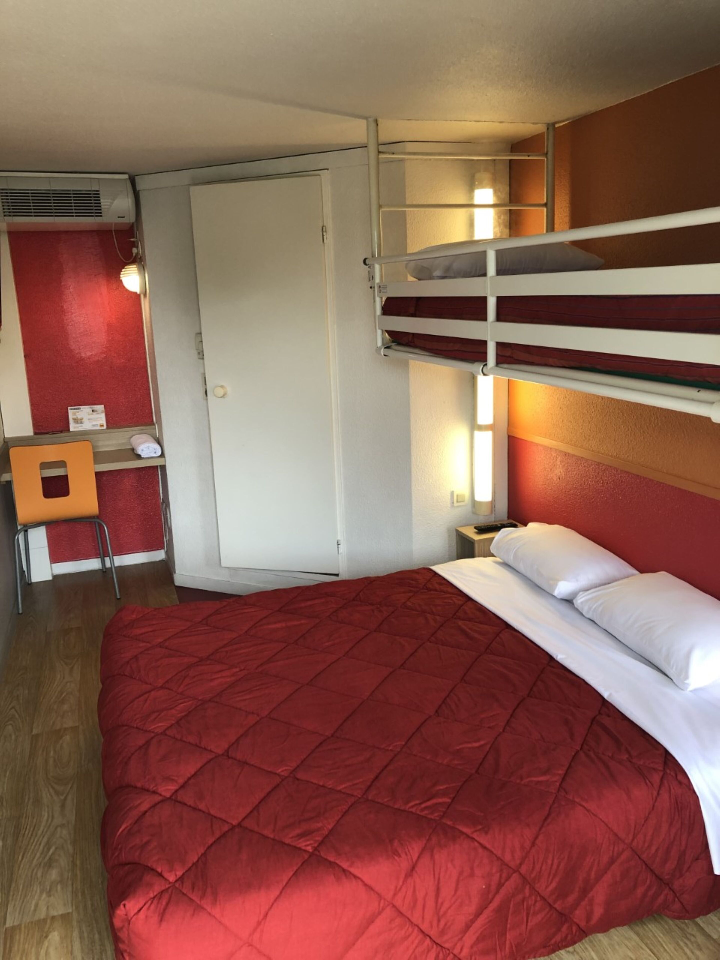 Ein Zimmer mit Etagenbetten, einem Schreibtisch und einem Stuhl.
