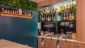 A bar area with shelves of liquor bottles, a bar counter, and a faucet. - Premiere Classe Laon (Laon)