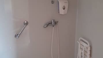 A bathroom with a toilet, a shower, and a hand dryer.