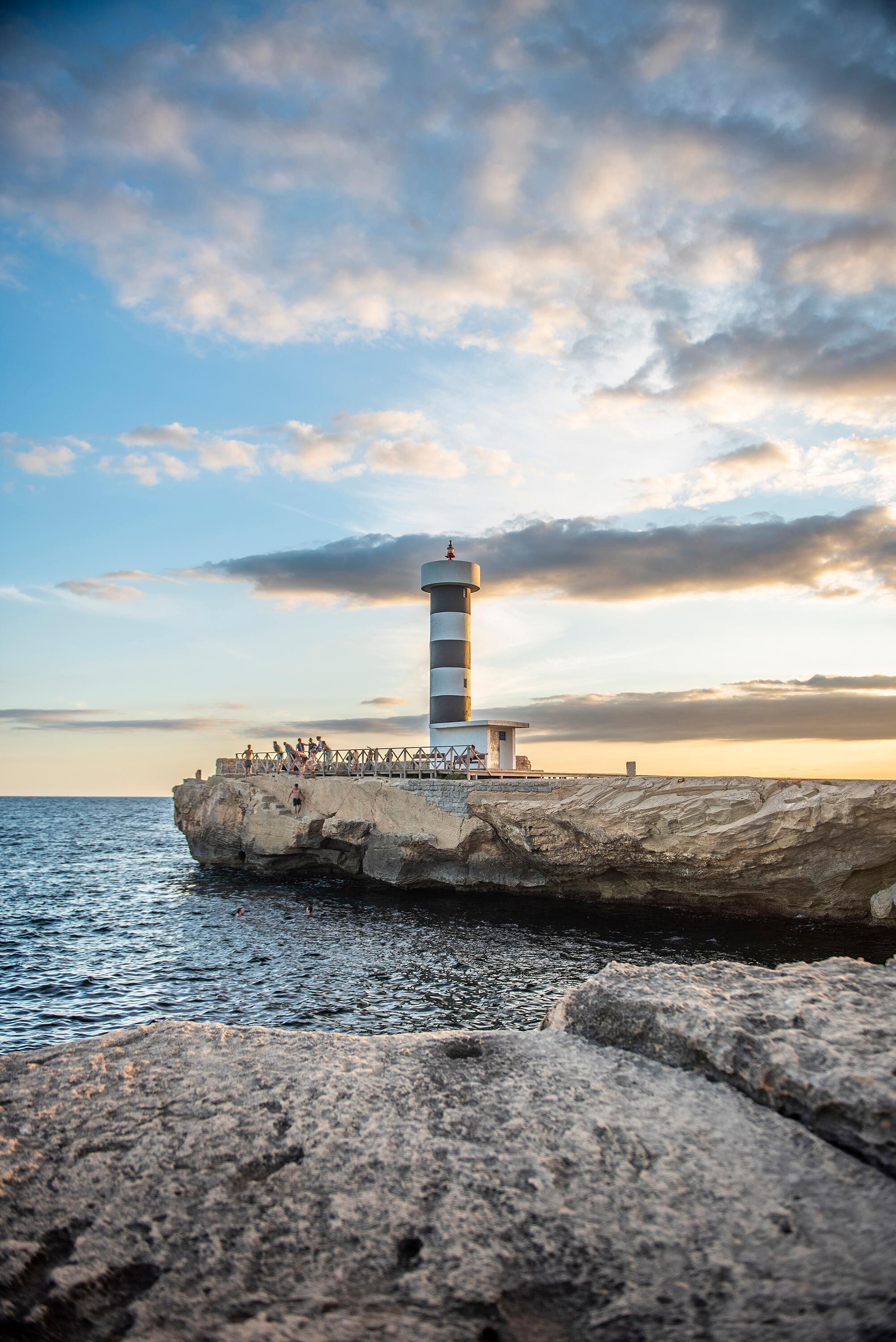 Un faro sobre un promontorio rocoso con una vista despejada del mar.