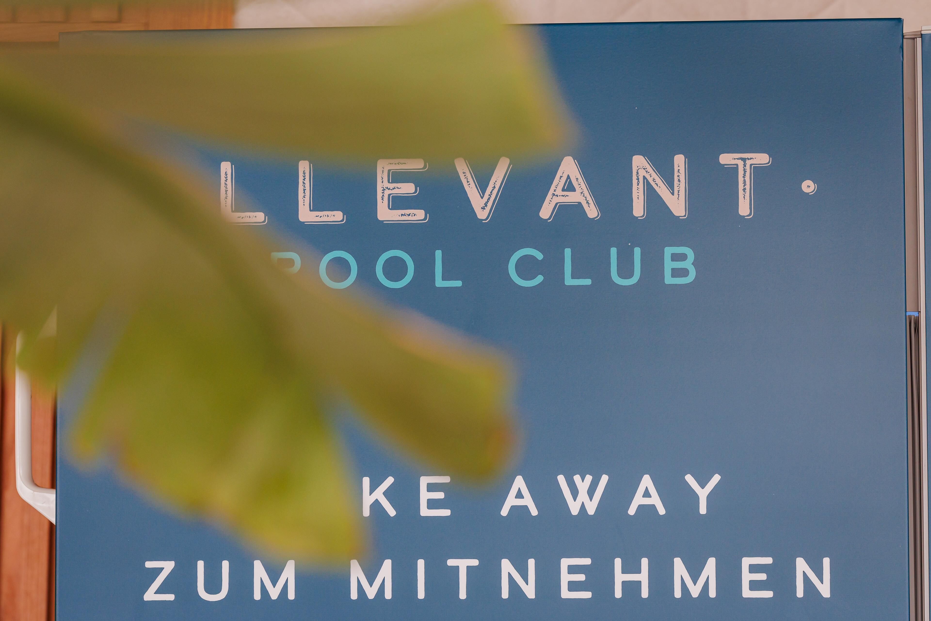 Une pancarte avec le texte : « LLEVANT SCHOOL CLUB KE AWAY ZUM MITNEHMEN ».