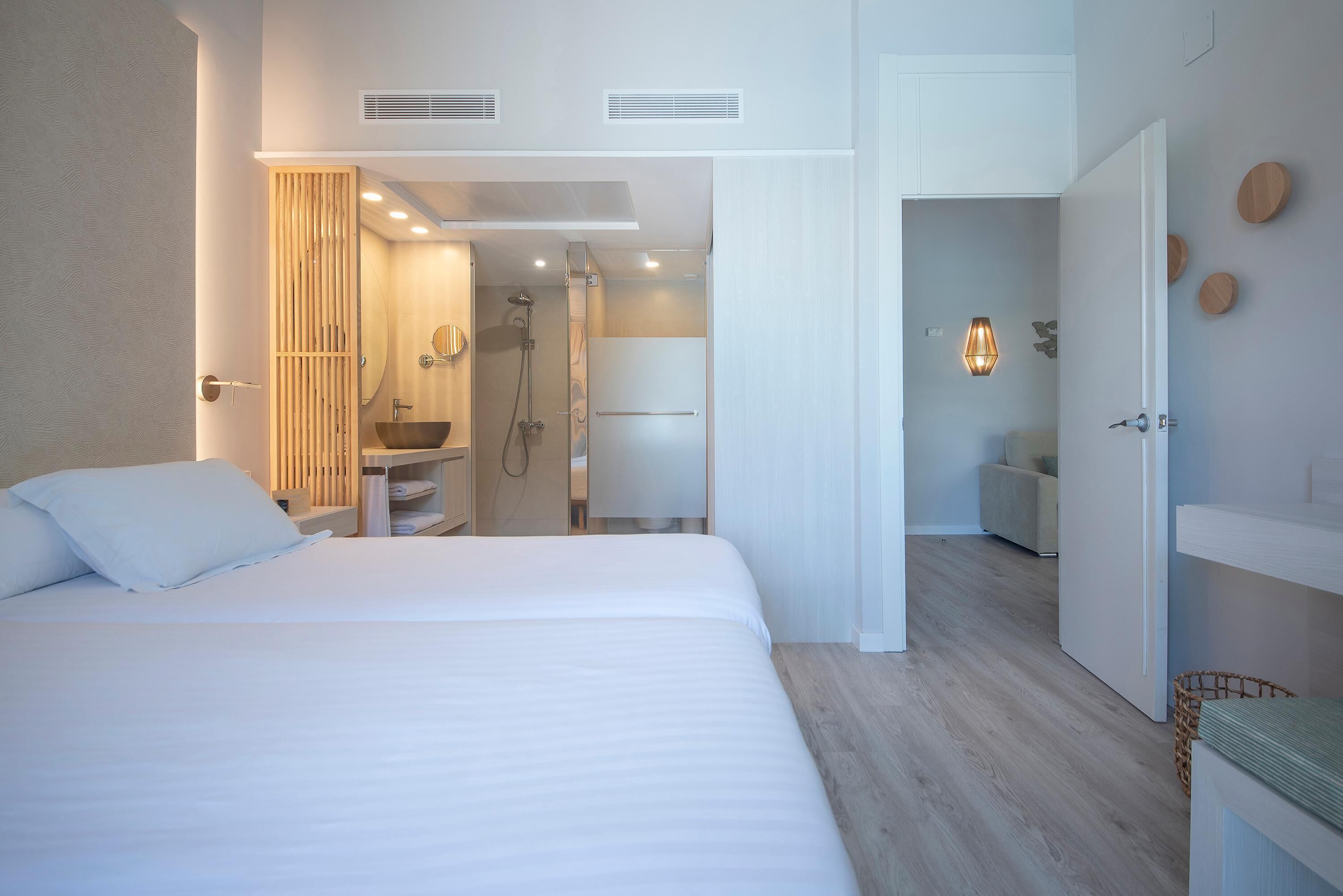 A modern hotel room with a large bed, a bathroom with a shower, and a walk-in closet.