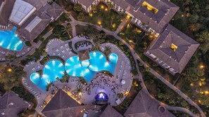 Vista aérea de un resort con varias piscinas, áreas de descanso y un edificio central con cúpula.