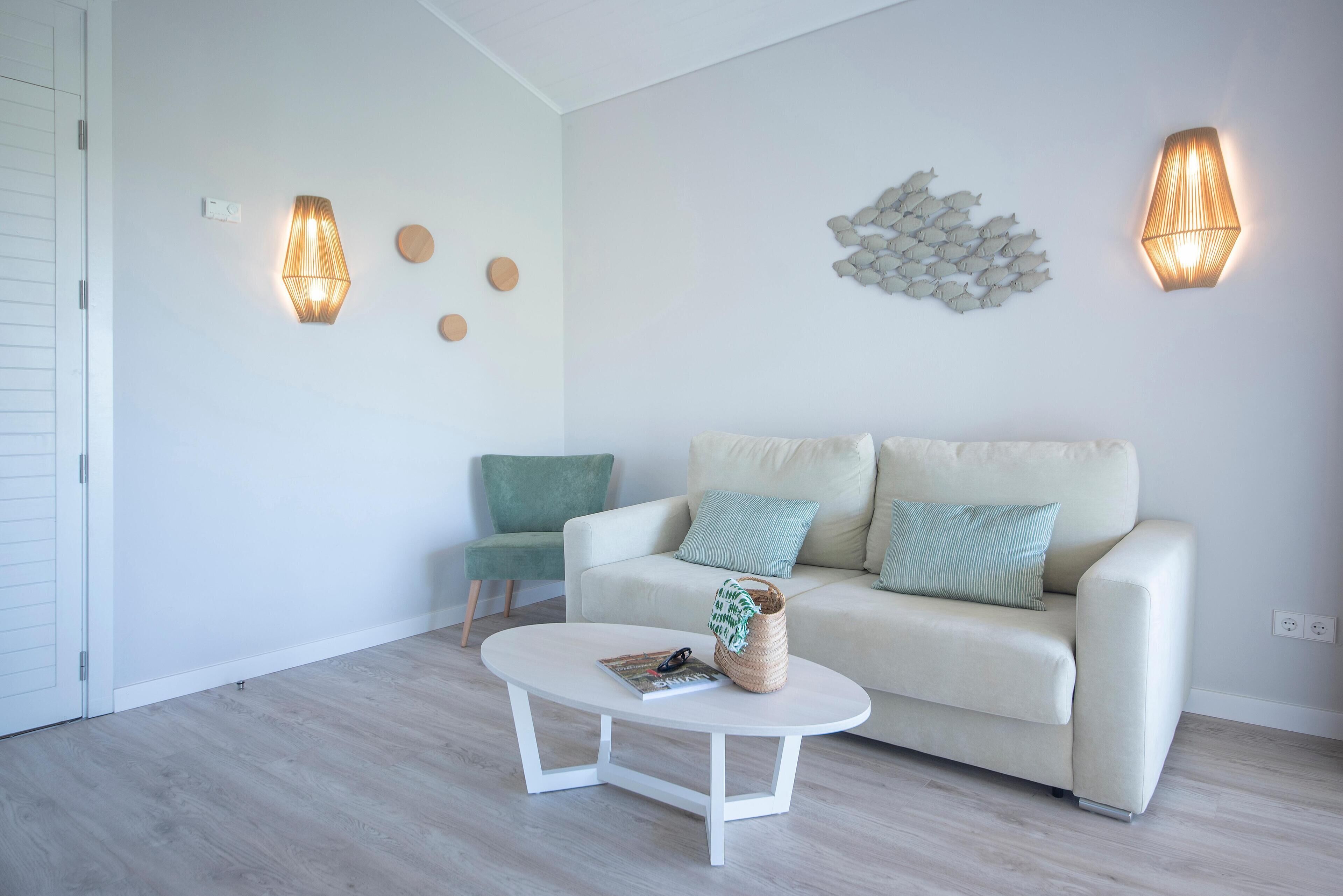 Ein modernes Wohnzimmer mit einem weißen Sofa, einem runden Couchtisch und zwei Wandleuchten.