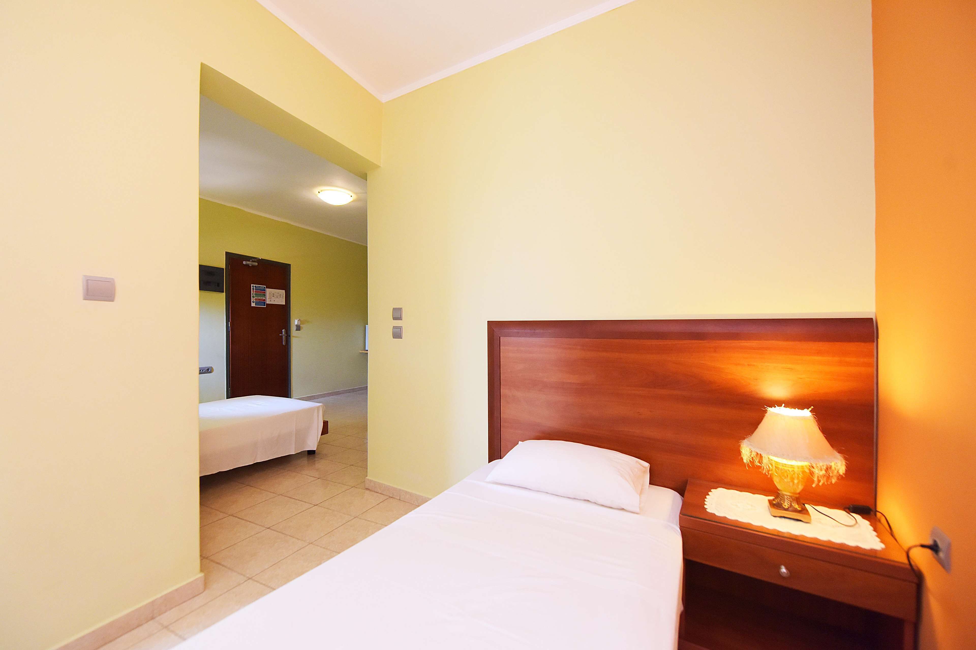 Une chambre d’hôtel avec un lit, une table de chevet avec une lampe et une porte donnant sur une autre pièce.