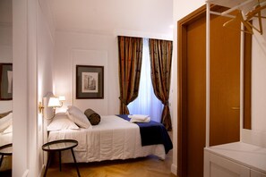 A neatly arranged bedroom with a bed, bedside lamp, and a framed picture on the wall. - Hotel Silva (Rome)