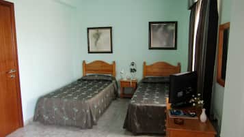 A room with two beds, a desk with a computer, and a TV.