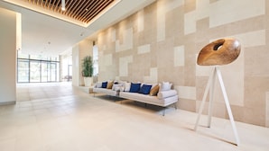 A spacious lobby with a modern white sofa, a potted plant, and a unique wooden sculpture. - Hotel Sipar Plava Laguna (Umag)