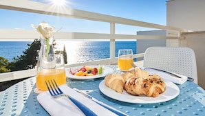 A table with breakfast items, a glass of orange juice, and a view of the ocean. - Hotel Sipar Plava Laguna (Umag)