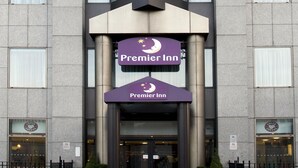 Een modern hotelgebouw met een opvallend 'Premier Inn'-bord, grote ramen en een symmetrische gevel.