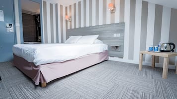 Una habitación de hotel con una cama, una mesita de noche de madera y una pared a rayas.