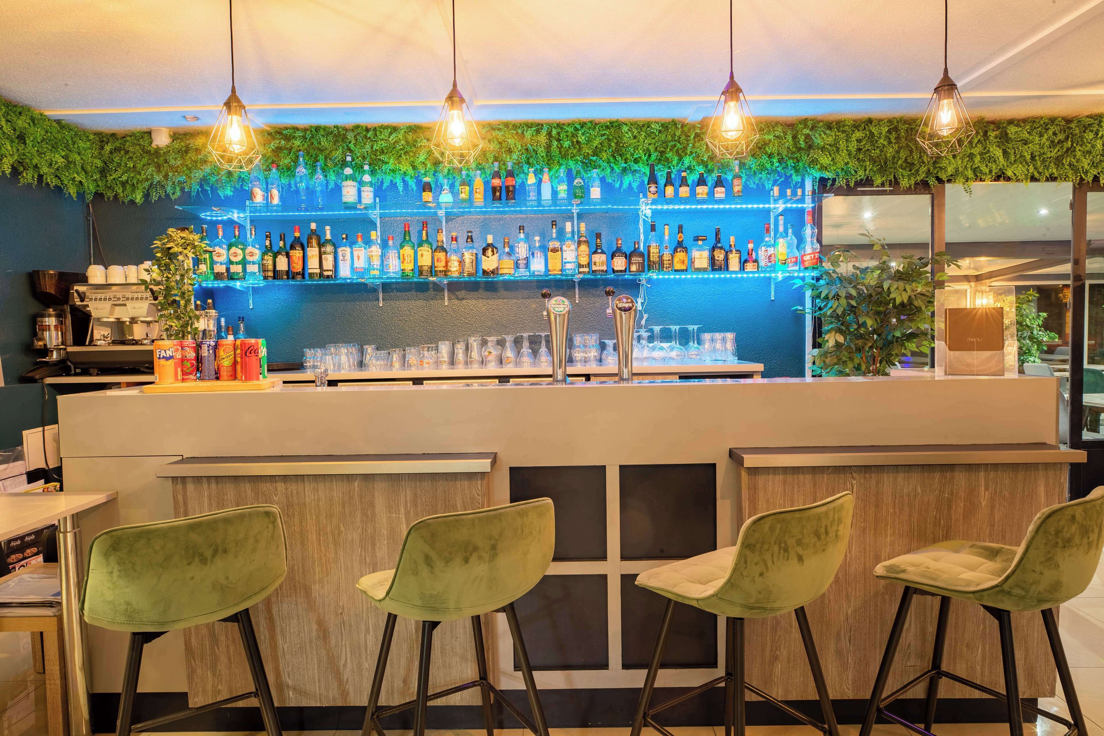 Eine Bar mit einer Theke, Barhocker und Regalen voller Flaschen.