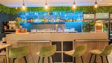 Eine Bar mit einer Theke, Barhocker und Regalen voller Flaschen.