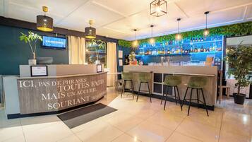 Zona de bar con barra, taburetes y un televisor de pared mostrando 'VALENCIENNES'.