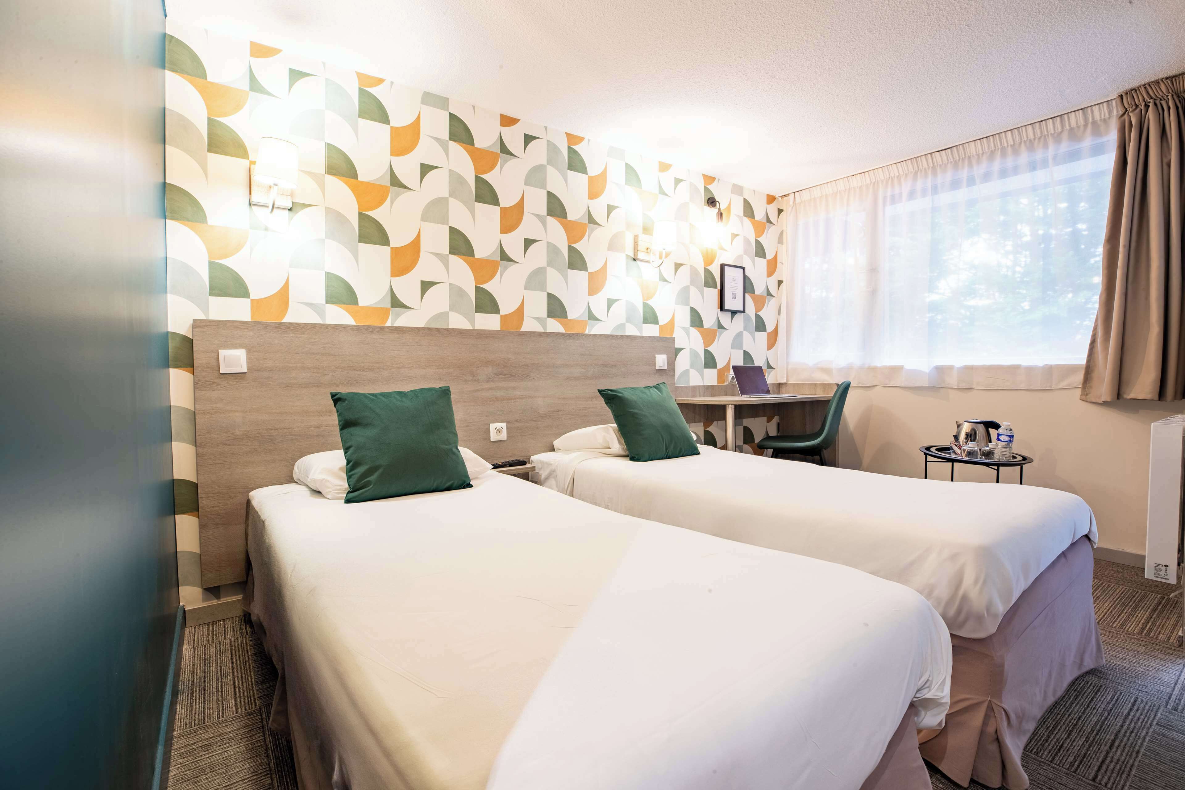 Une chambre d’hôtel avec deux lits, un bureau et une chaise.