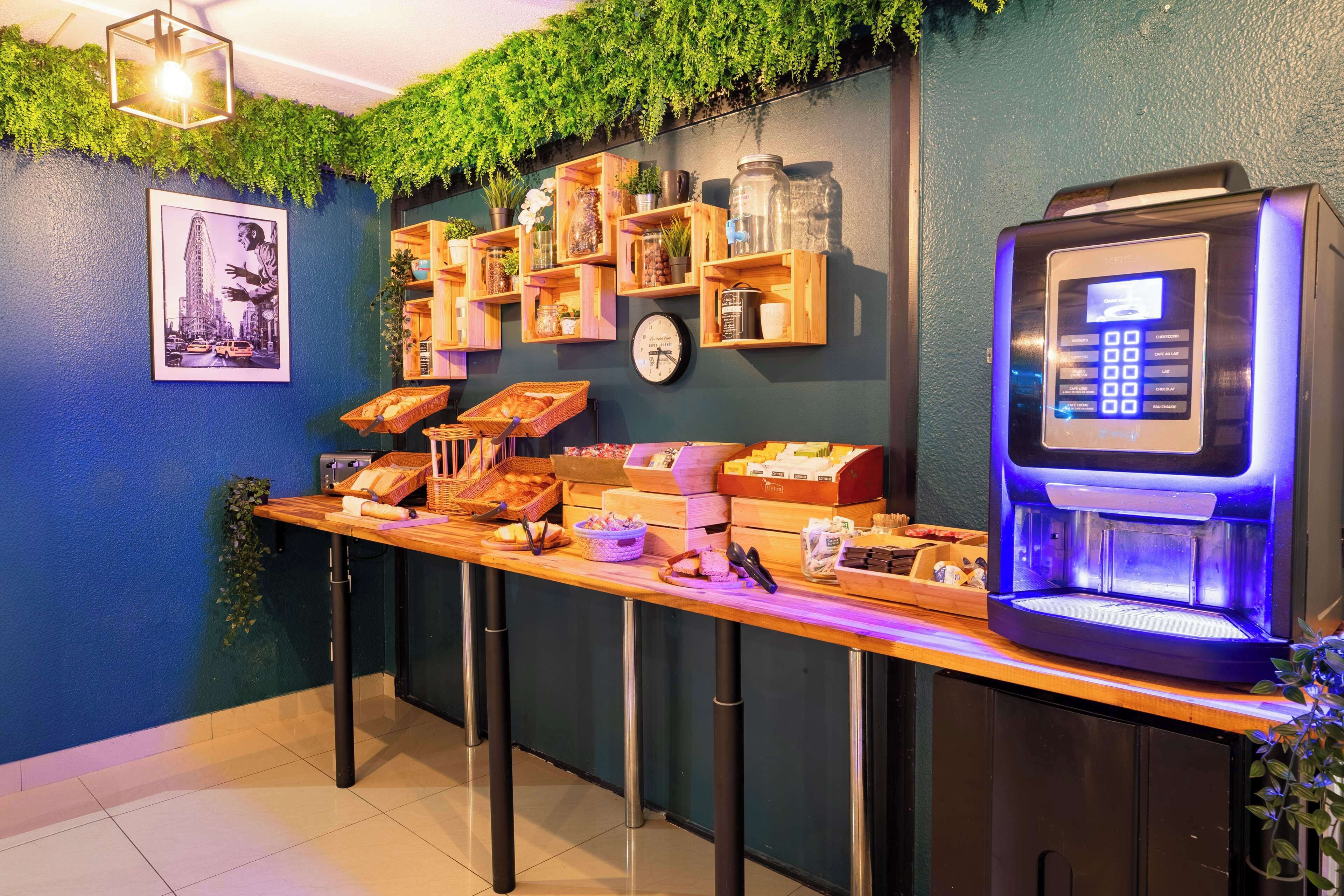 Un espace bar avec un comptoir en bois, des étagères remplies de bocaux et de plantes, une horloge et un distributeur automatique de boissons en libre-service.
