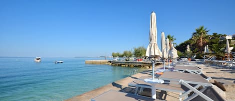 Een privéstrand, ligstoelen aan het strand, parasols, strandlakens