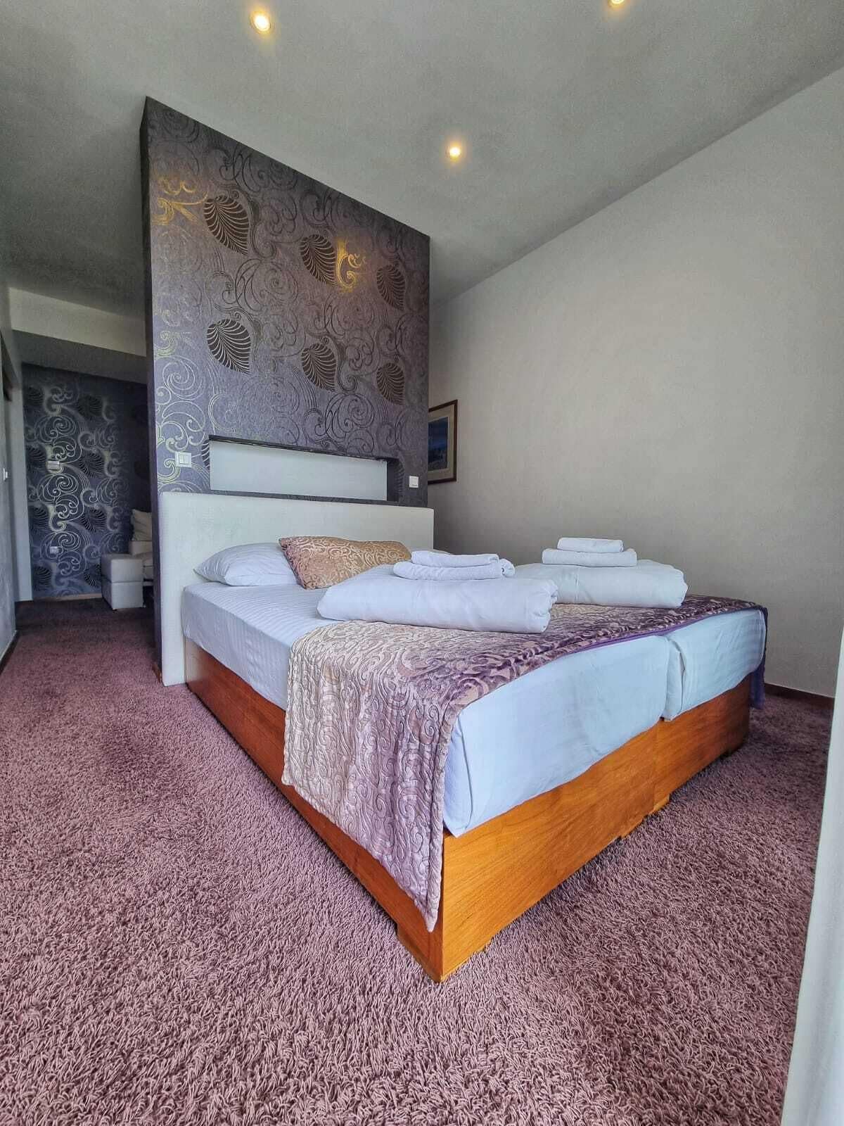 A bedroom with a large bed, a headboard, and a patterned wall.
