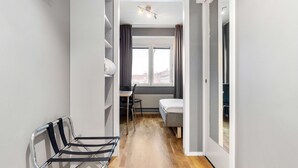 A narrow hallway with a bed, a desk, and a chair in a modern apartment. - Sure Hotel by Best Western Stockholm Alvsjo (Älvsjö)