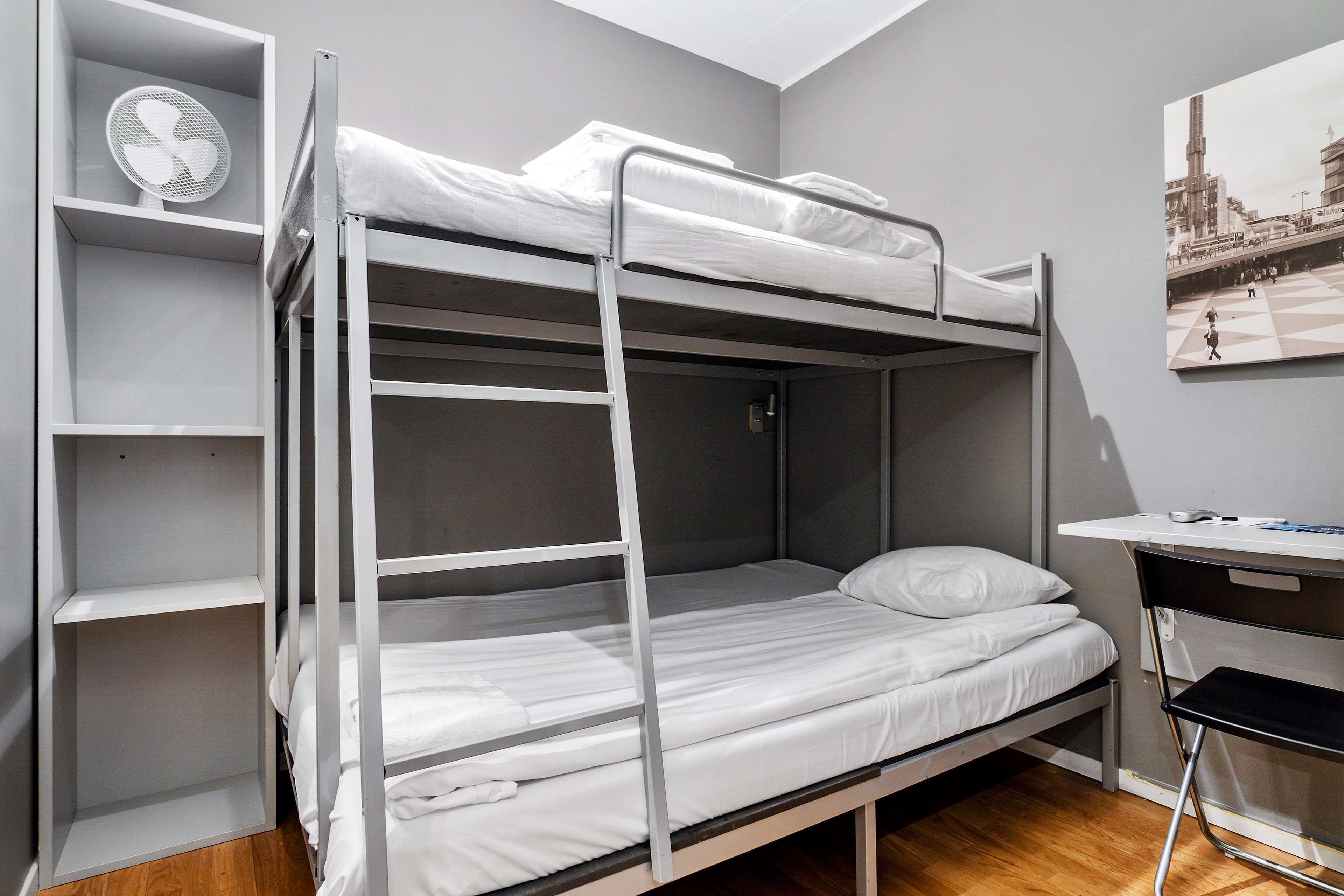 A bunk bed room with a desk and a fan.