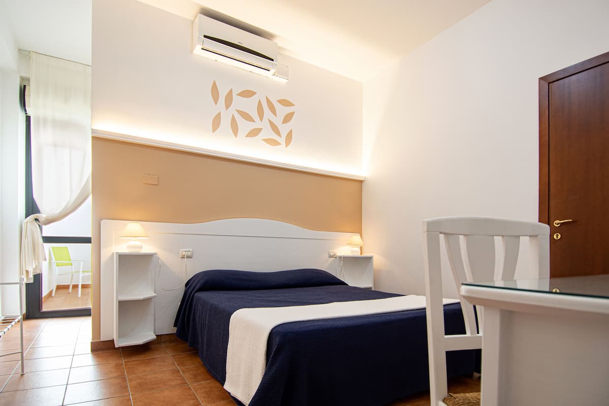 Une chambre d’hôtel comprenant un lit, des tables de chevet, une chaise et une armoire.