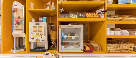 Een ontbijtbalk met een koffieapparaat, broodrooster en een koelkast vol etenswaren.