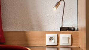 Un bureau en bois, une lampe de bureau, une prise de courant et un interrupteur.