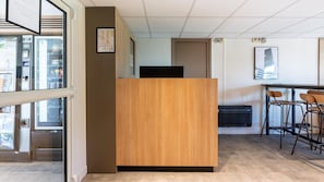 Un moderno spazio ufficio con una reception in legno, una zona bar con sgabelli e un'ampia vetrata con vista sulla città.