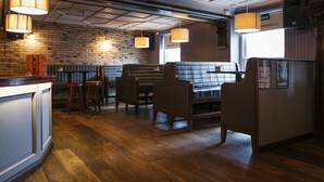 A restaurant with wooden flooring, brick walls, and a bar area with stools.