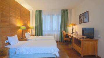 Ein Hotelzimmer mit zwei Betten, einem Schreibtisch, einem Fernseher und einem Stuhl.