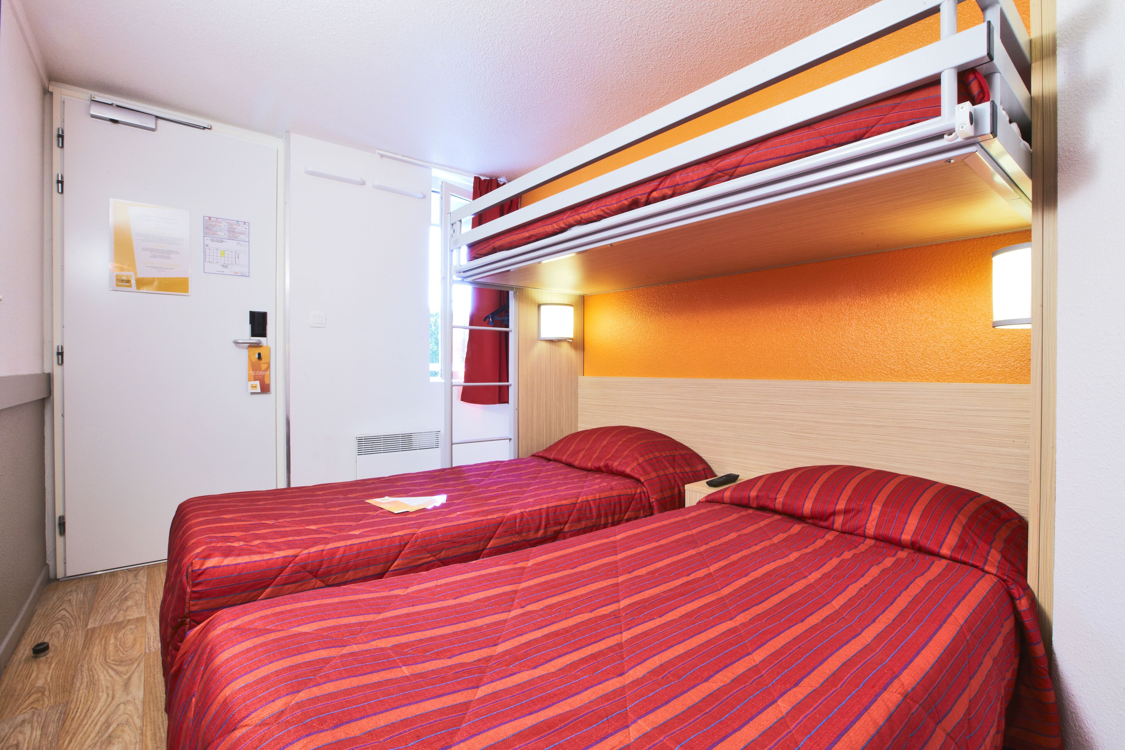 A room with two beds, a white wardrobe, and a door with a notice.