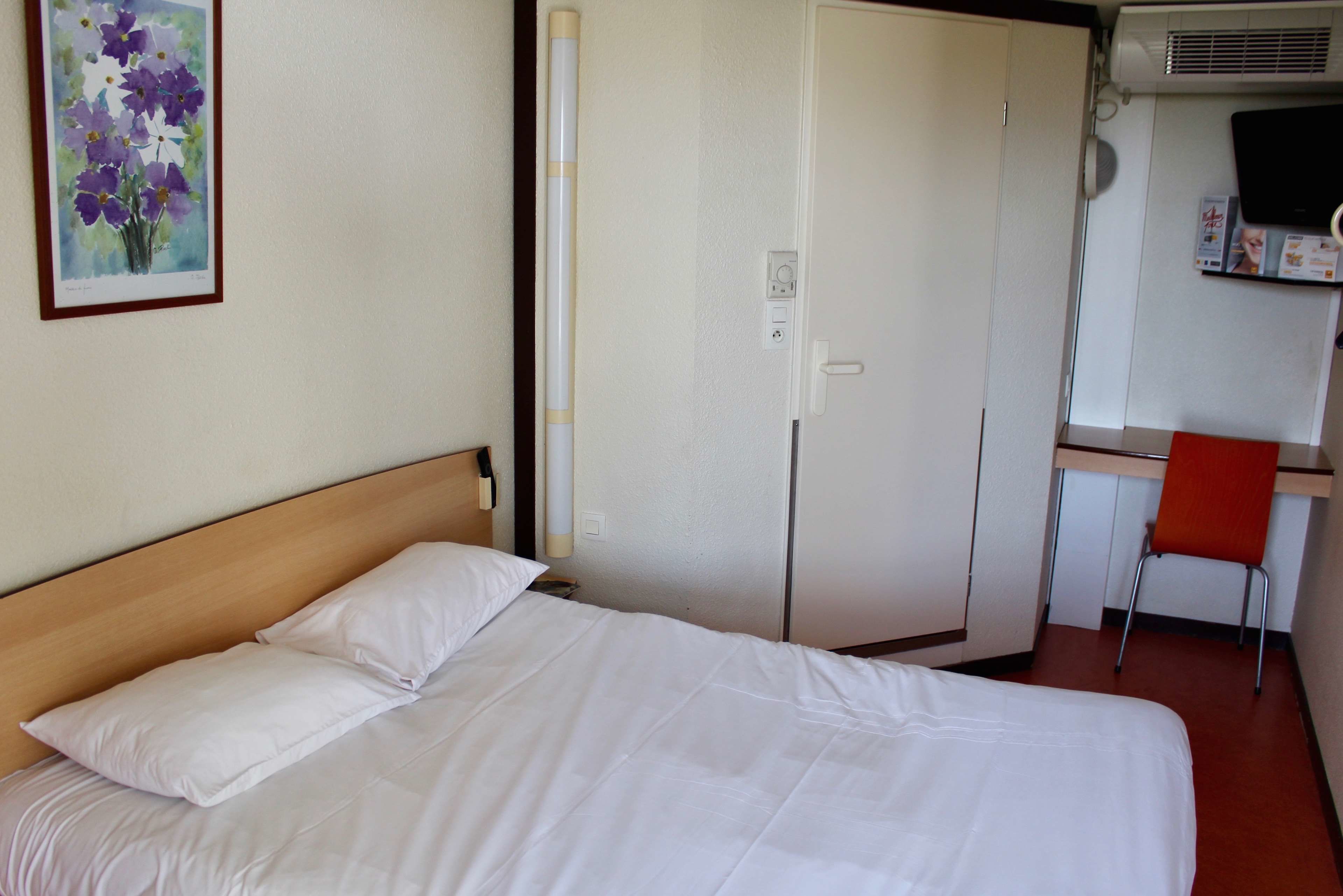 A hotel room with a bed, a desk, and a chair.