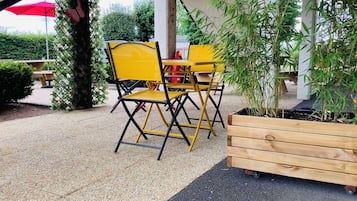 Un espace extérieur aménagé avec des chaises jaunes et un banc en bois.