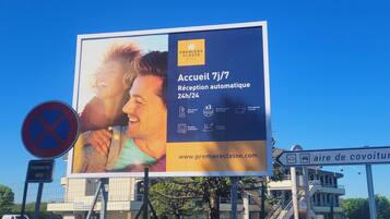 A billboard advertising a hotel with automatic 24/7 reception, a private bathroom, and a dining area.