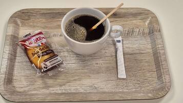 Een kop koffie met een lepel op een houten dienblad.