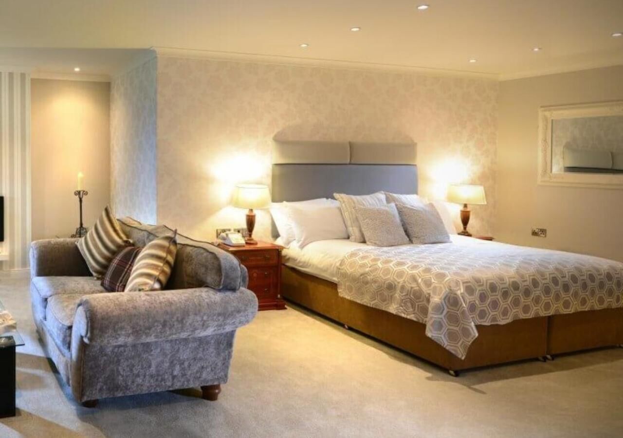 A bedroom with a large bed, two bedside tables, a chair, and a lamp.