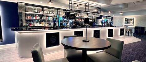 Un moderno bar con mostrador, asientos y una variedad de botellas de licor.
