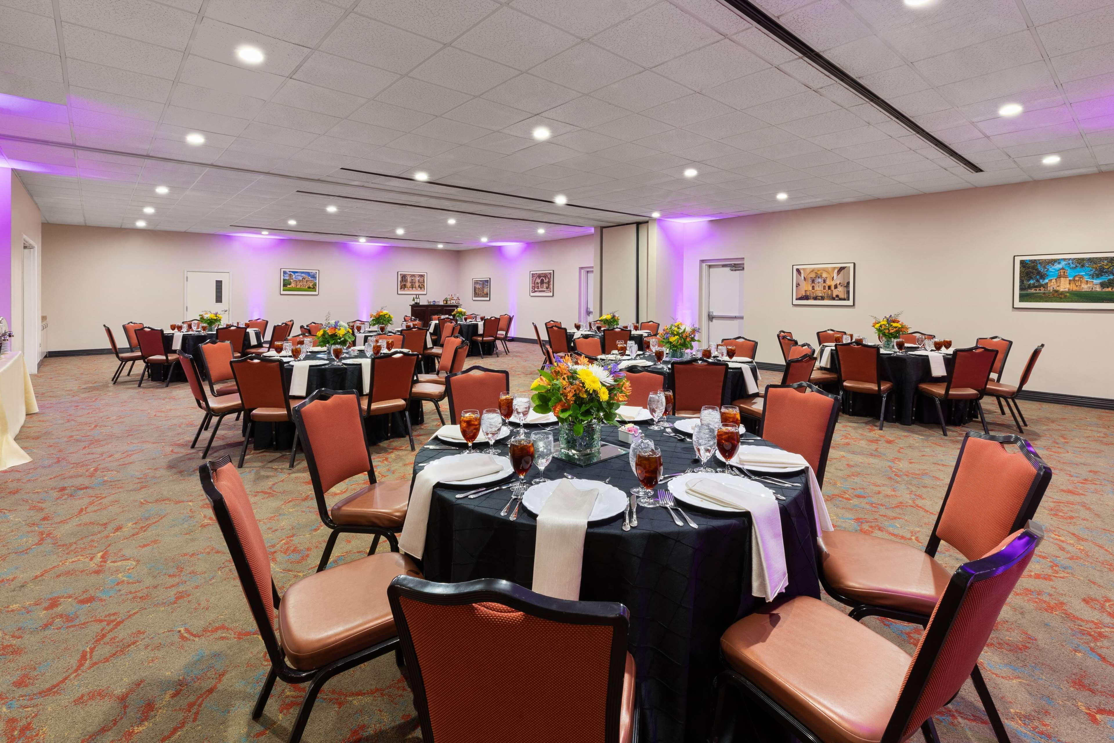 A conference room with round tables, orange chairs, and purple lighting.
